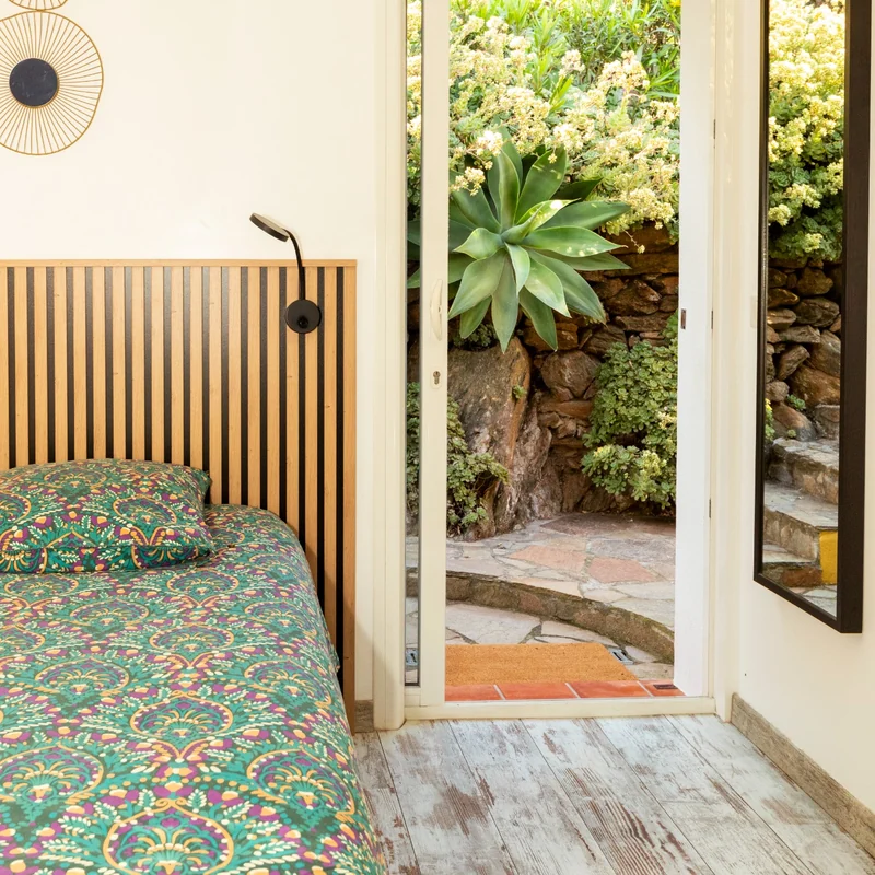 Studio Brava : lit double près de la fenêtre ouverte sur le jardin